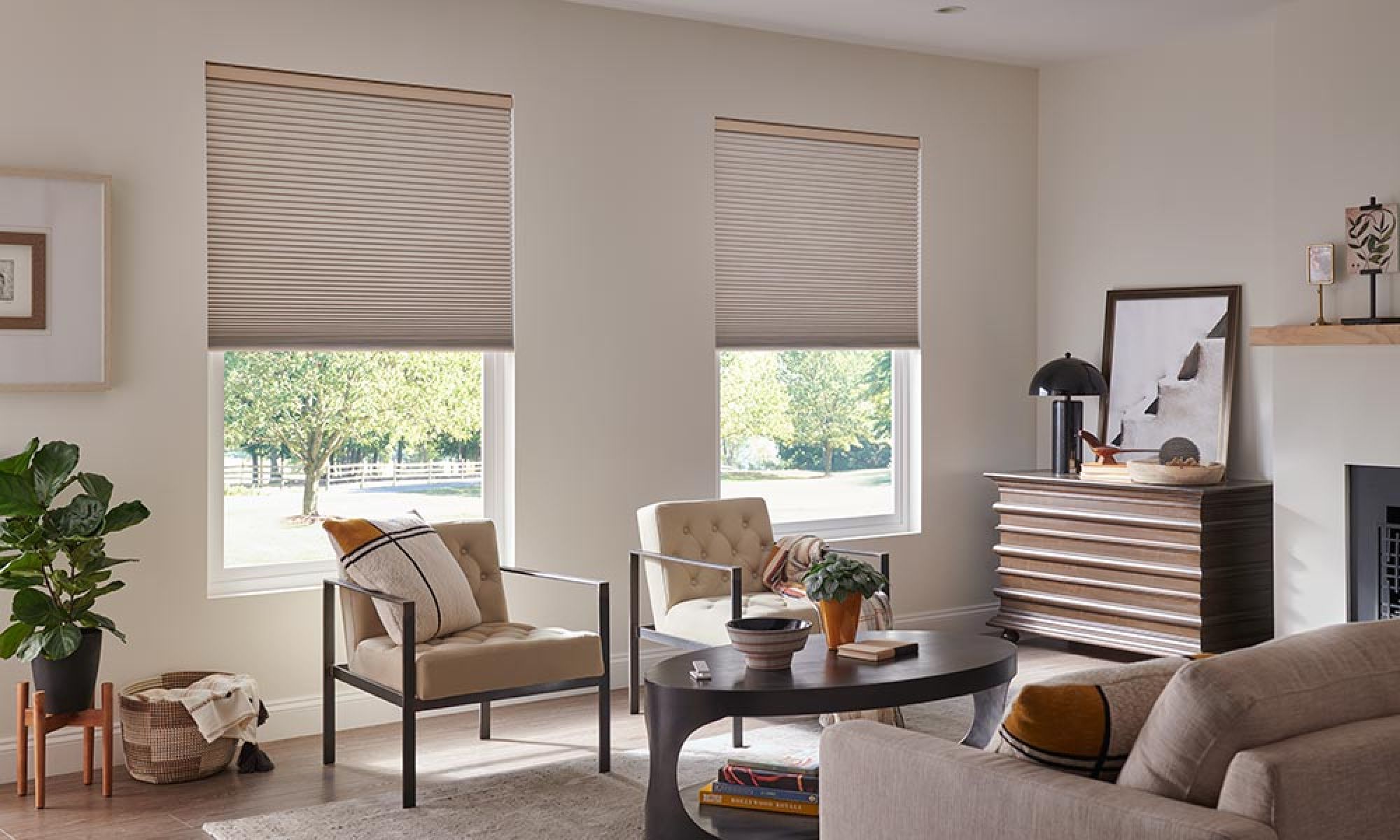 A cozy living room with automated window shades partially closed, featuring comfortable seating and decorative elements.