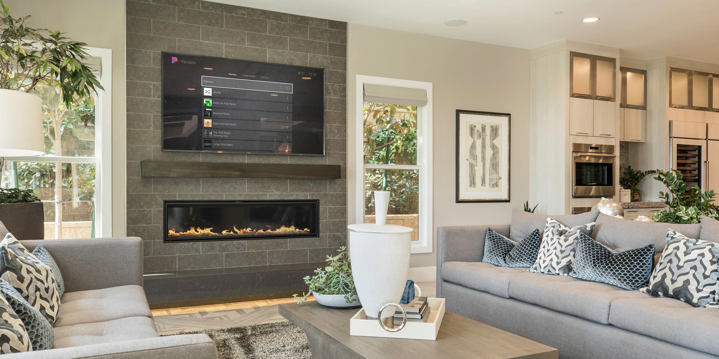 A cozy family room with a large TV mounted above a modern fireplace and a plush sofa facing the screen.