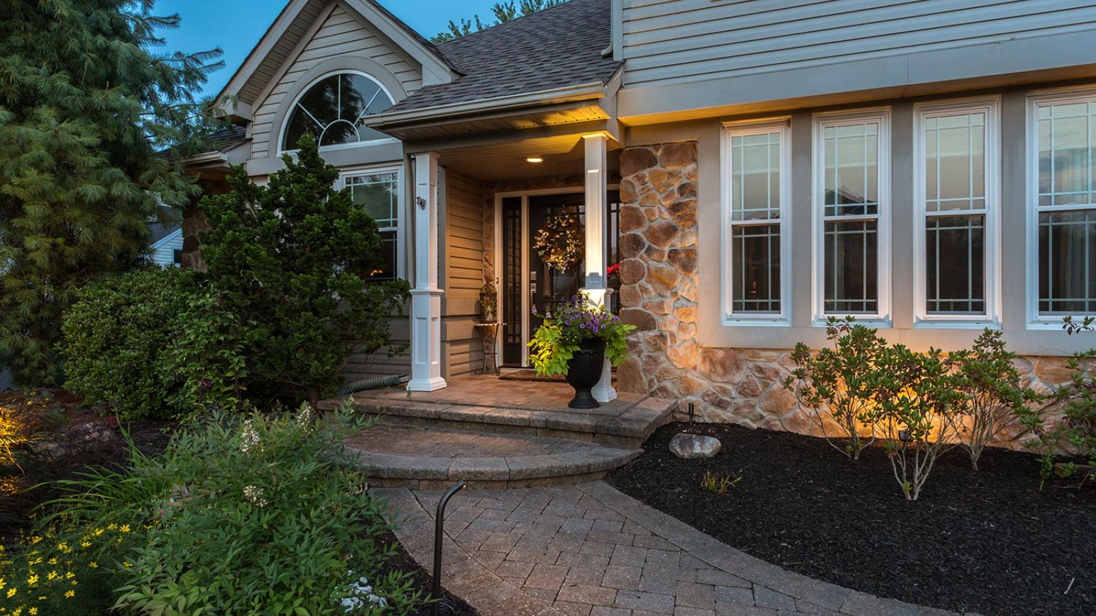 Cozy front porch of a traditional house with illuminated plants and inviting decor.