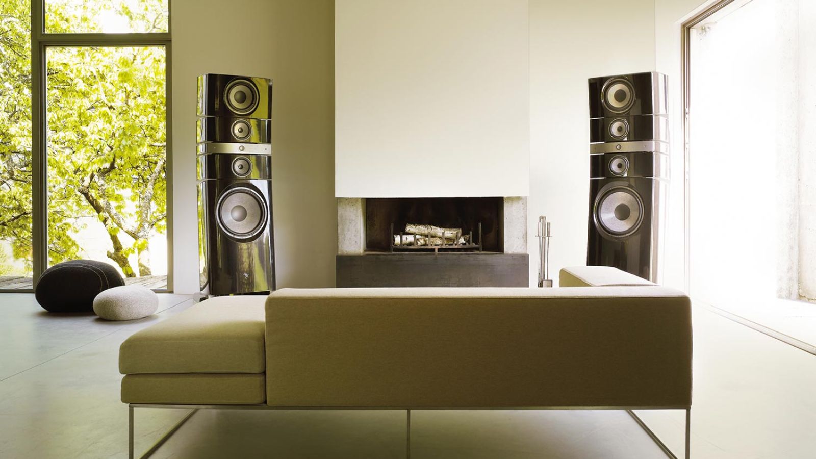 Contemporary room with towering high-end speakers, a sleek fireplace, and a lush garden view.