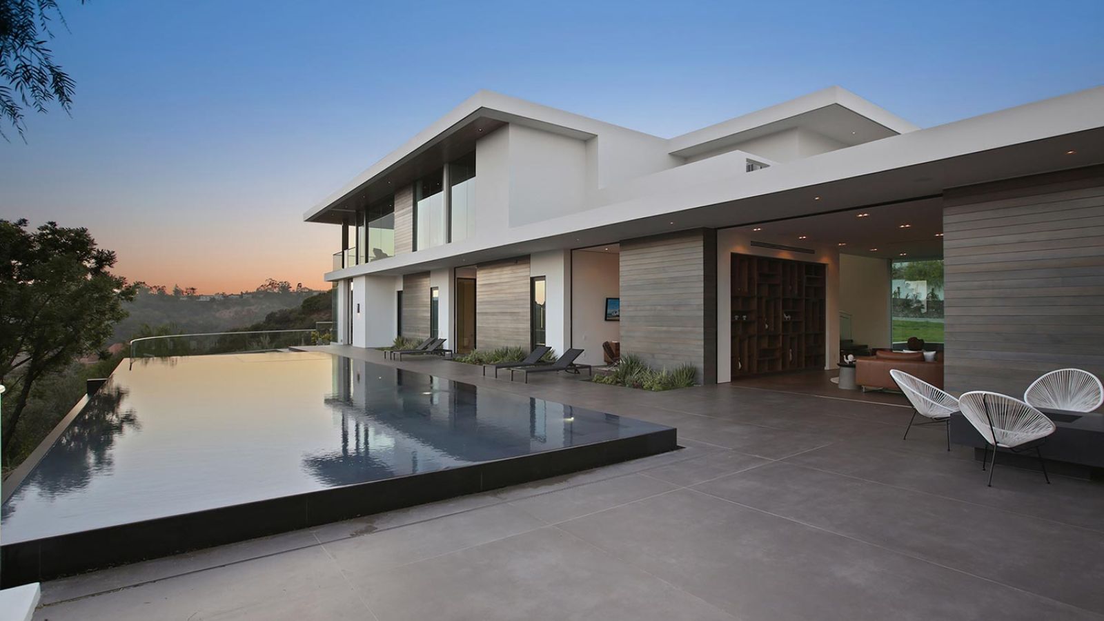 Infinity pool reflecting the sunset with a contemporary house in the background.