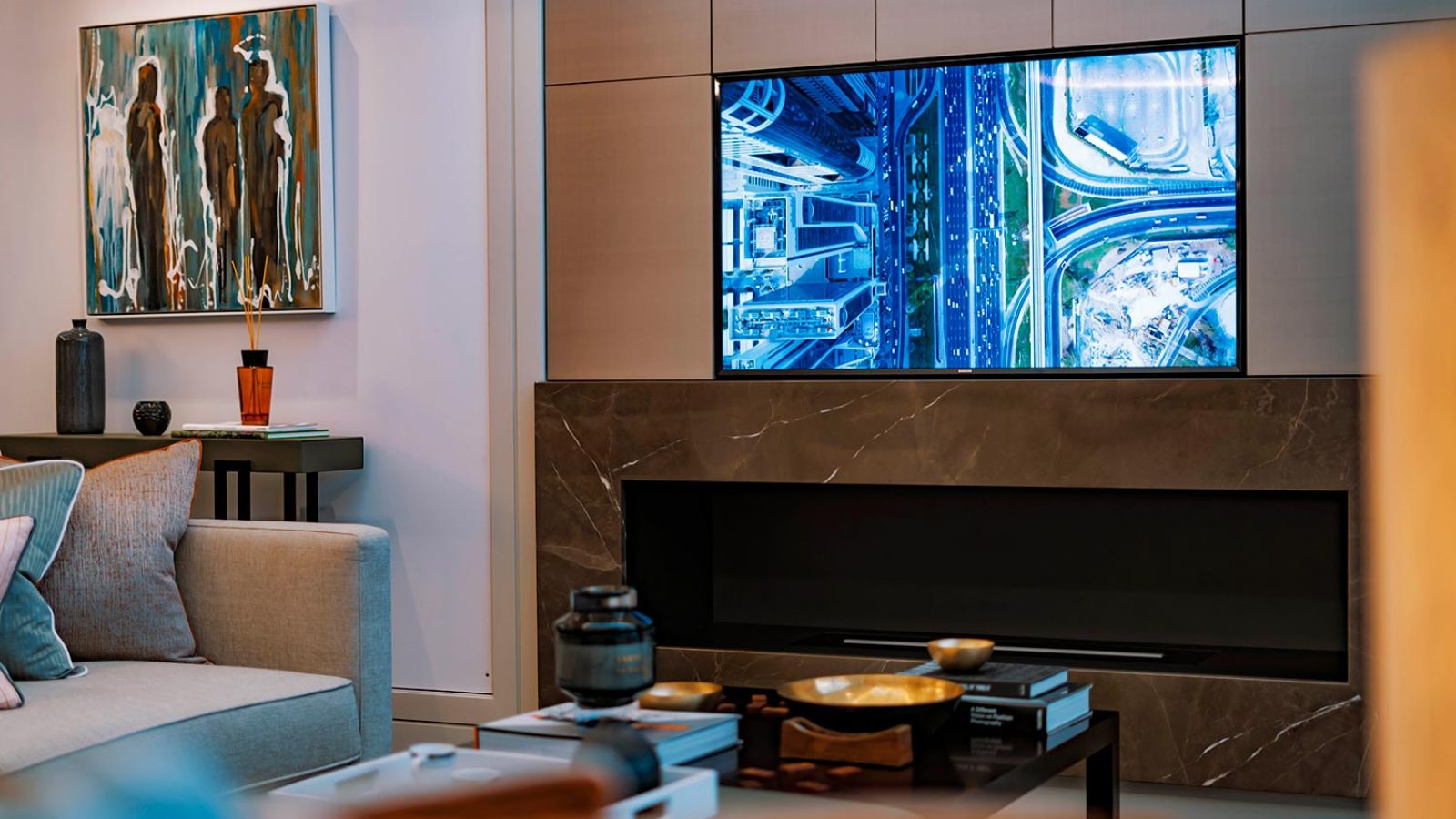 Modern living room with a mounted TV displaying abstract visuals, surrounded by curated decor.