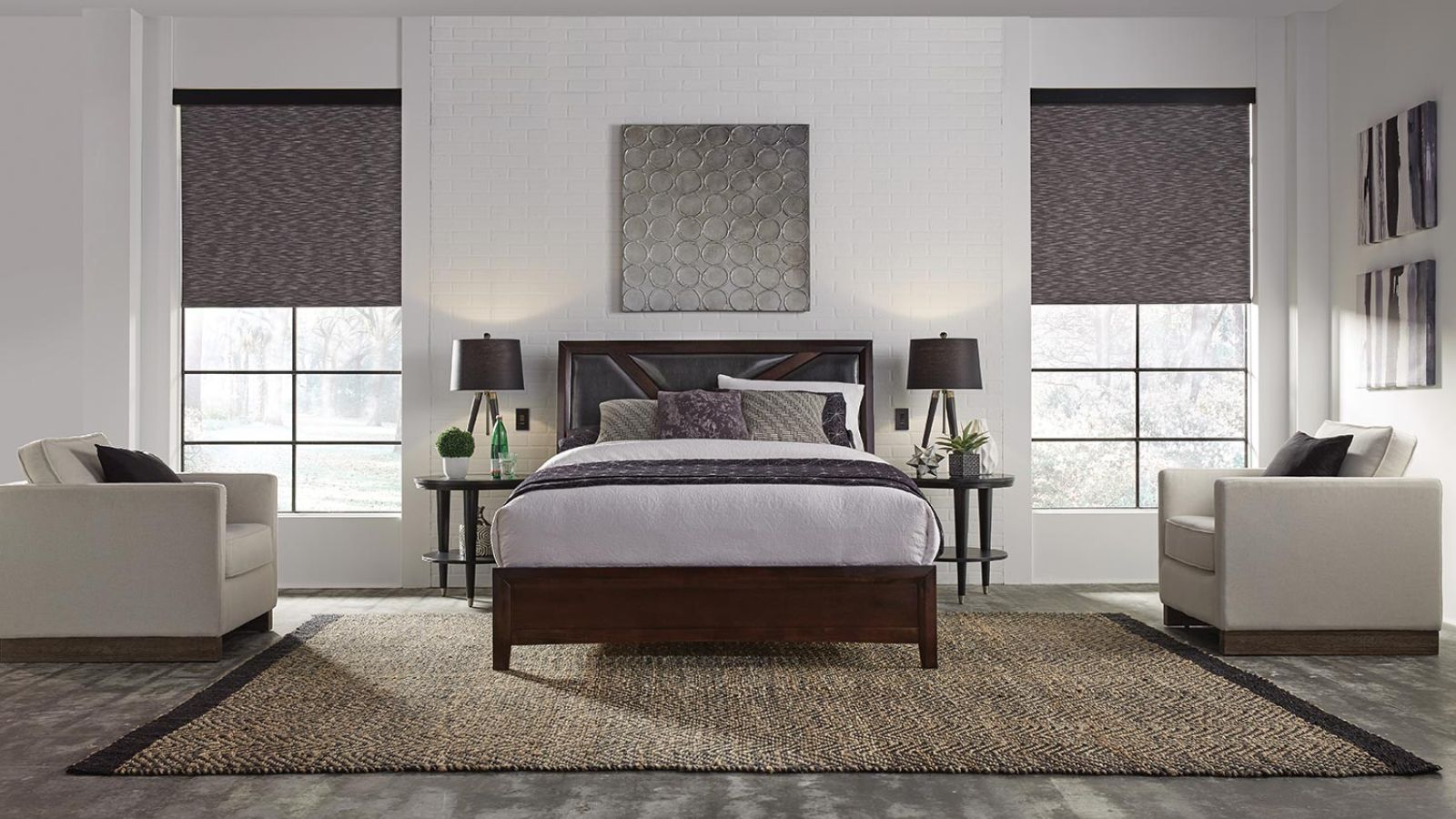 A cozy bedroom featuring a dark wood bedframe, matching side tables, and dual lamps, accented by large windows with textured gray shades.