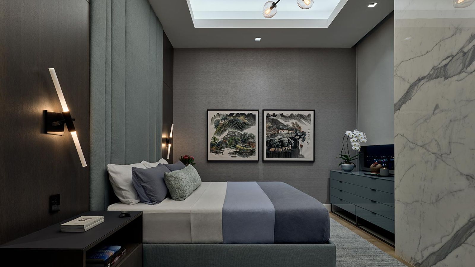 A luxurious bedroom with moody lighting, wall-mounted lights, a marble feature wall, and artistic decor.