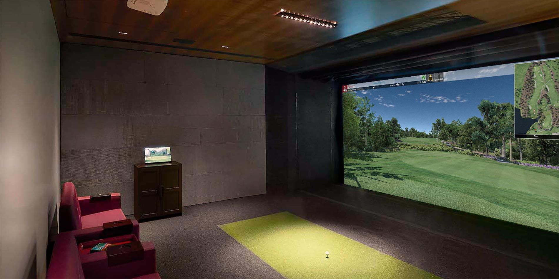 A personal golf simulator room with comfortable seating and a large screen showing a virtual golf course.