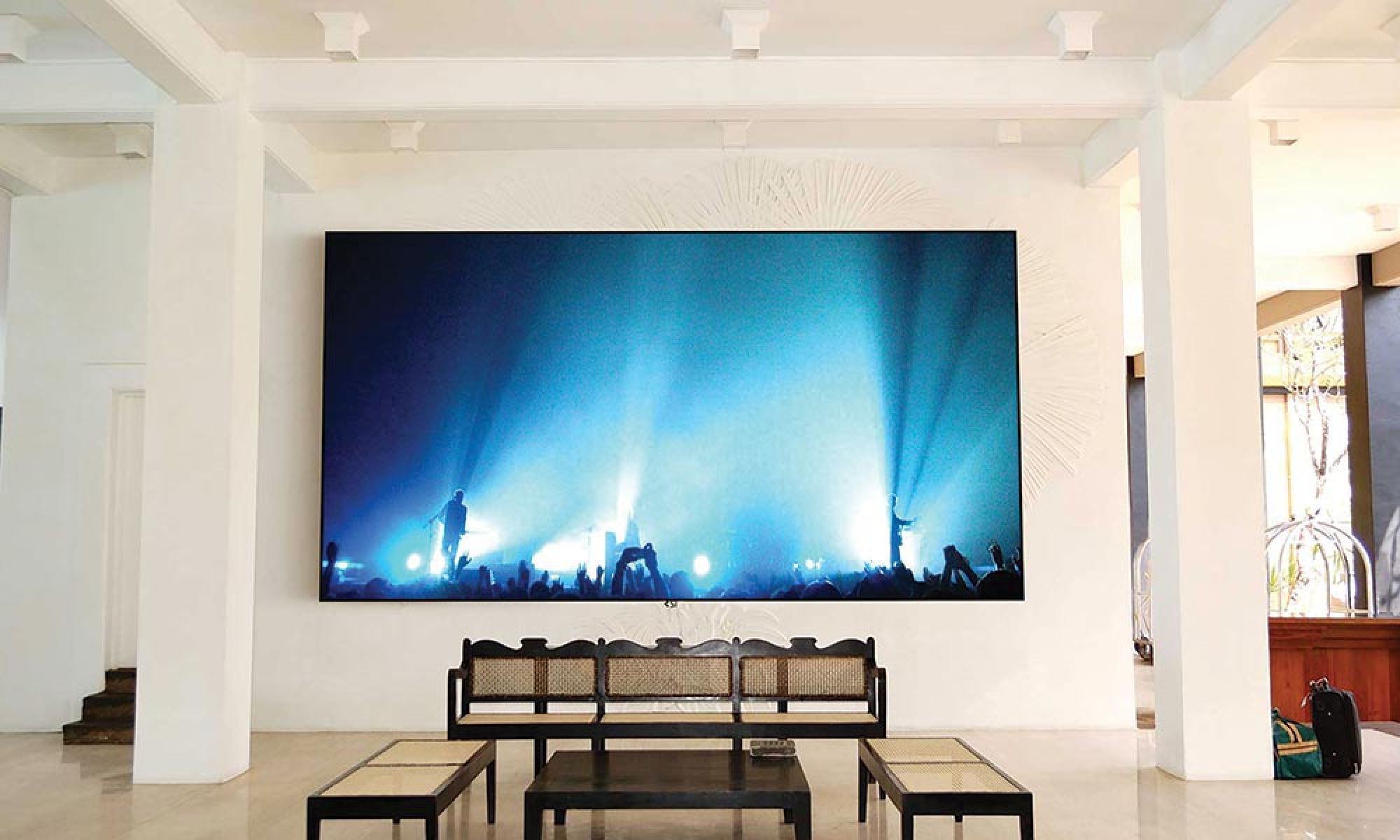 A large projection screen displaying a concert scene in an expansive, modern living space.